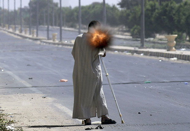 A rebel on crutches fires a rocket propelled grenade while fighting on the front line in Sirte