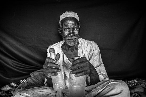 The most important things that Torjam was able to bring with him were the plastic bottles he holds here. One carried drinking water, the other cooking oil. "All I could carry was this, and an axe. We couldn't bring much, and even had to leave some other old people behind.